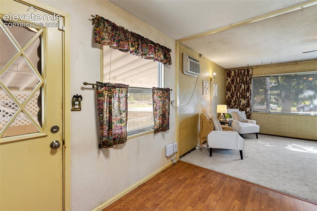 Image 12 of 45: Wood-finish flooring leading to carpeted living area with window-mounted ai