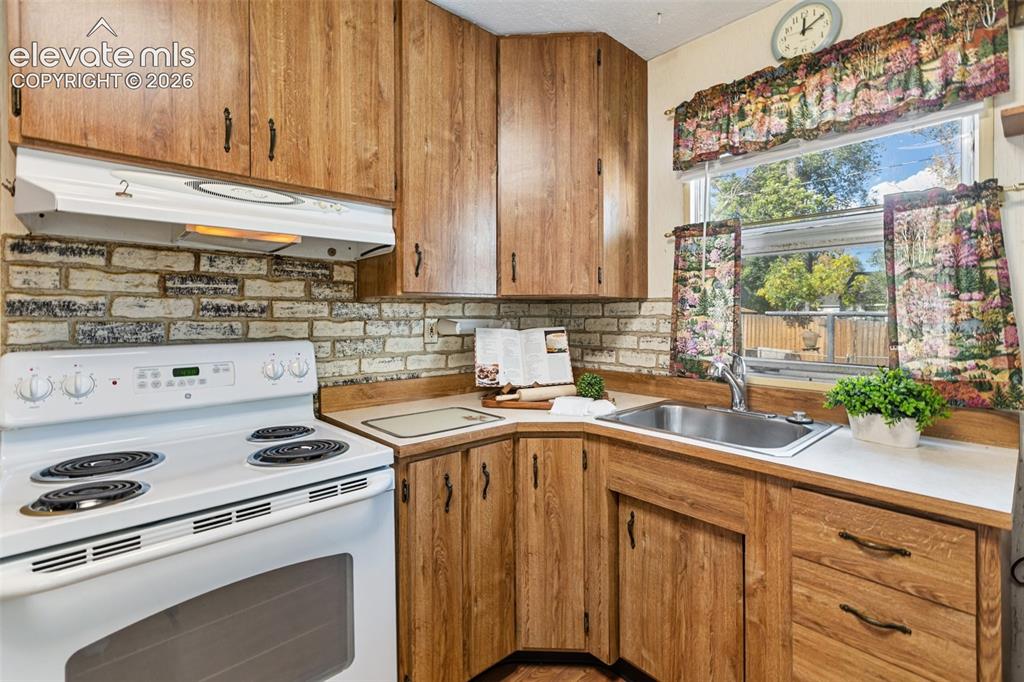 Image 15 of 45: White electric range with an overhead exhaust hood