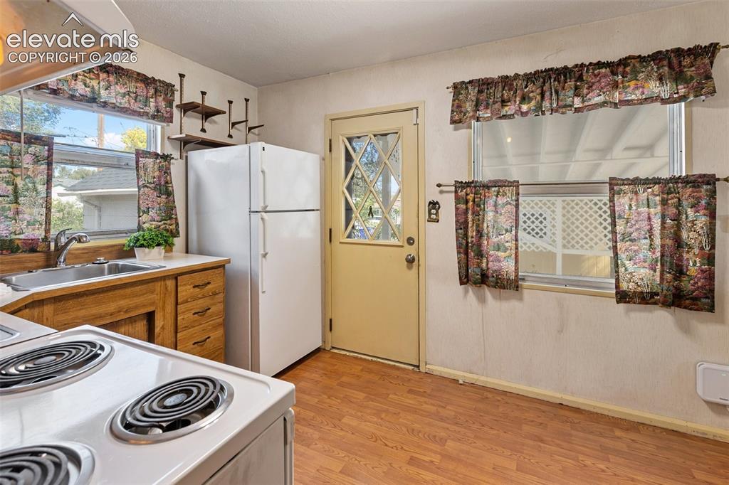 Image 16 of 45: Kitchen featuring wood-finish flooring, white appliances, and a stainless s