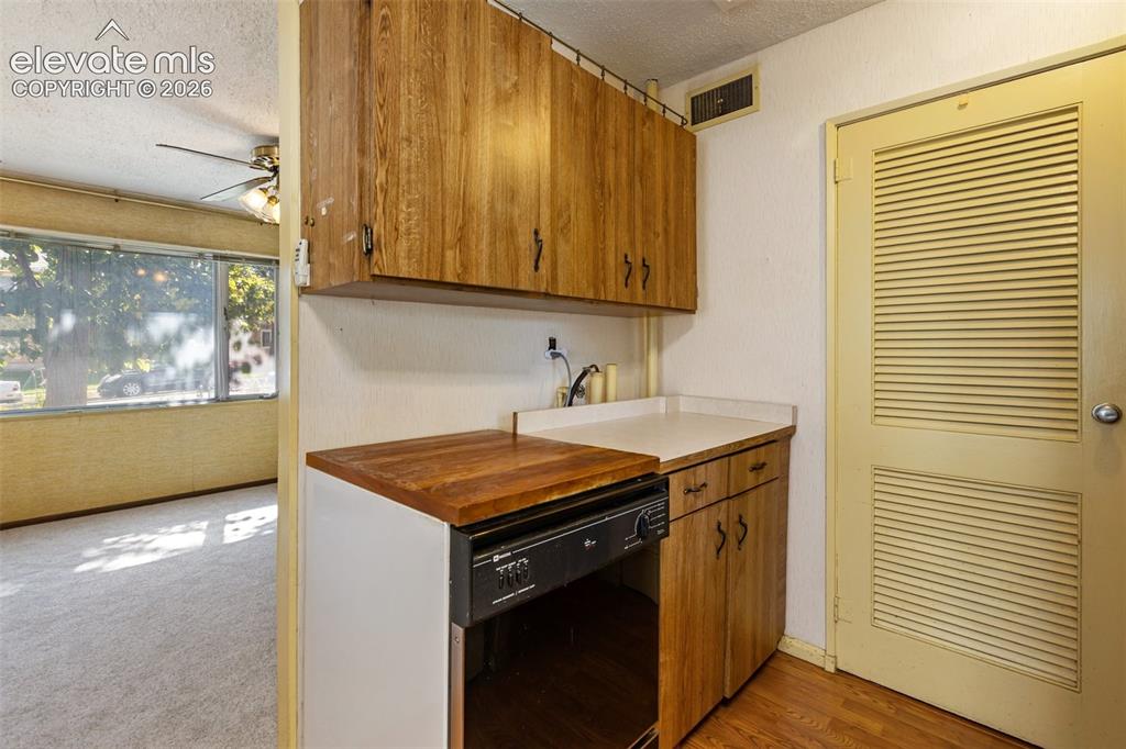 Image 18 of 45: Kitchenette with wood-finish cabinetry, solid surface countertop, and integ