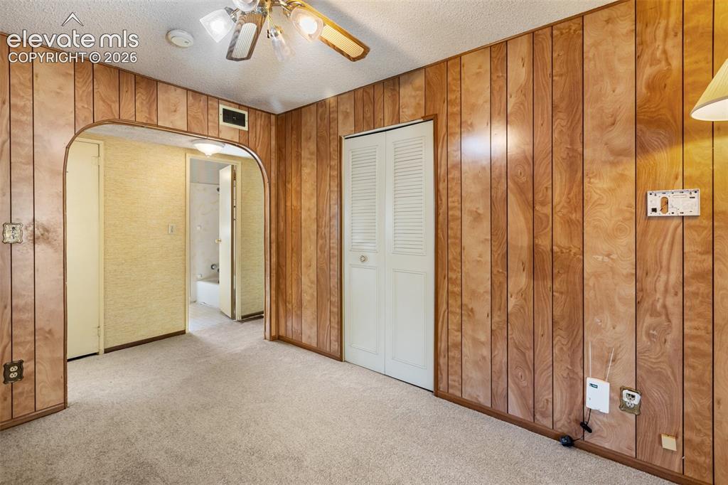 Image 27 of 45: Wood-paneled walls and neutral carpet flooring