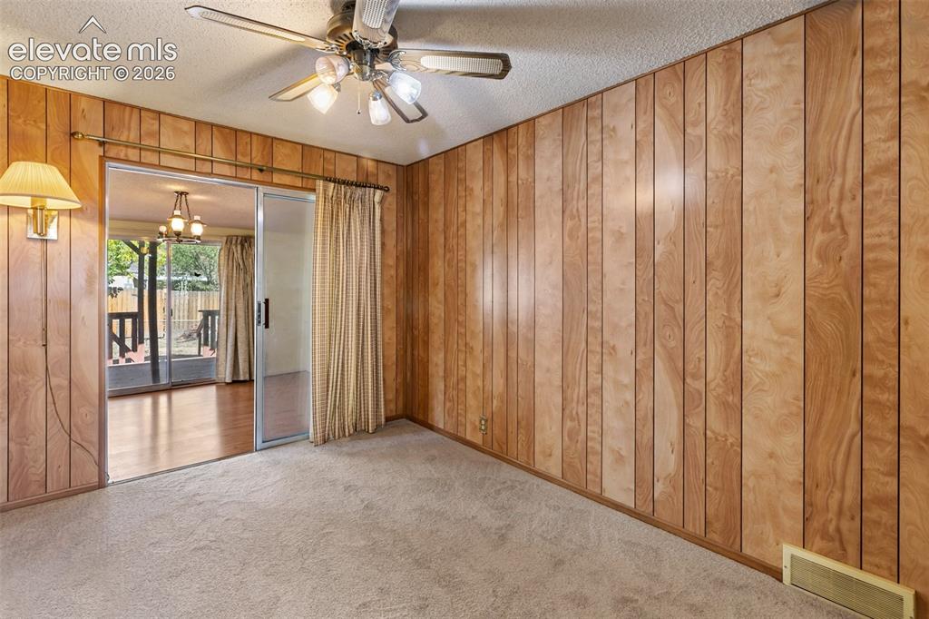 Image 30 of 45: Wood-paneled walls featuring a sliding glass door, overhead ceiling fan, an