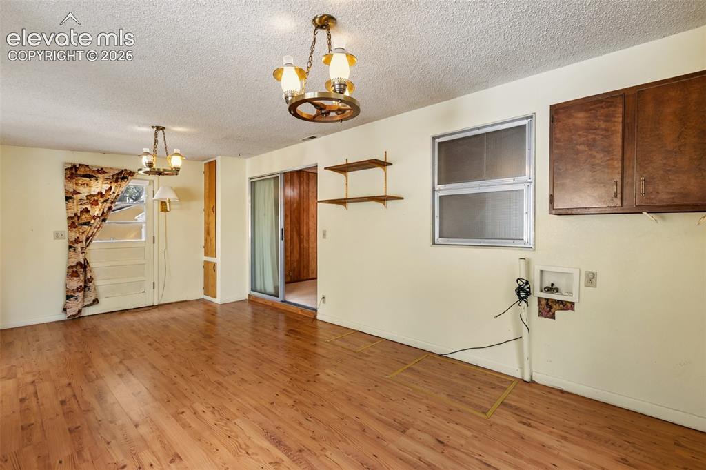 Image 34 of 45: Wood-finish flooring throughout, two chandelier fixtures, sliding glass doo