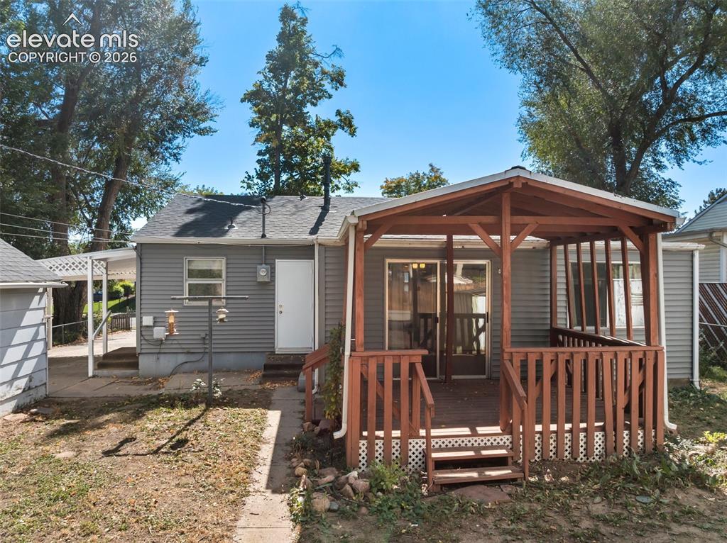 Image 38 of 45: Covered deck with wood railing, leading to a sliding glass door