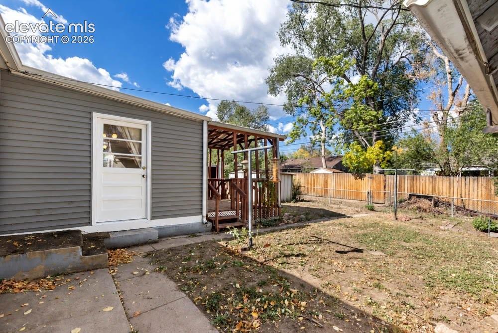 Image 39 of 45: Backyard featuring a privacy fence, covered deck, and a mix of grass and co