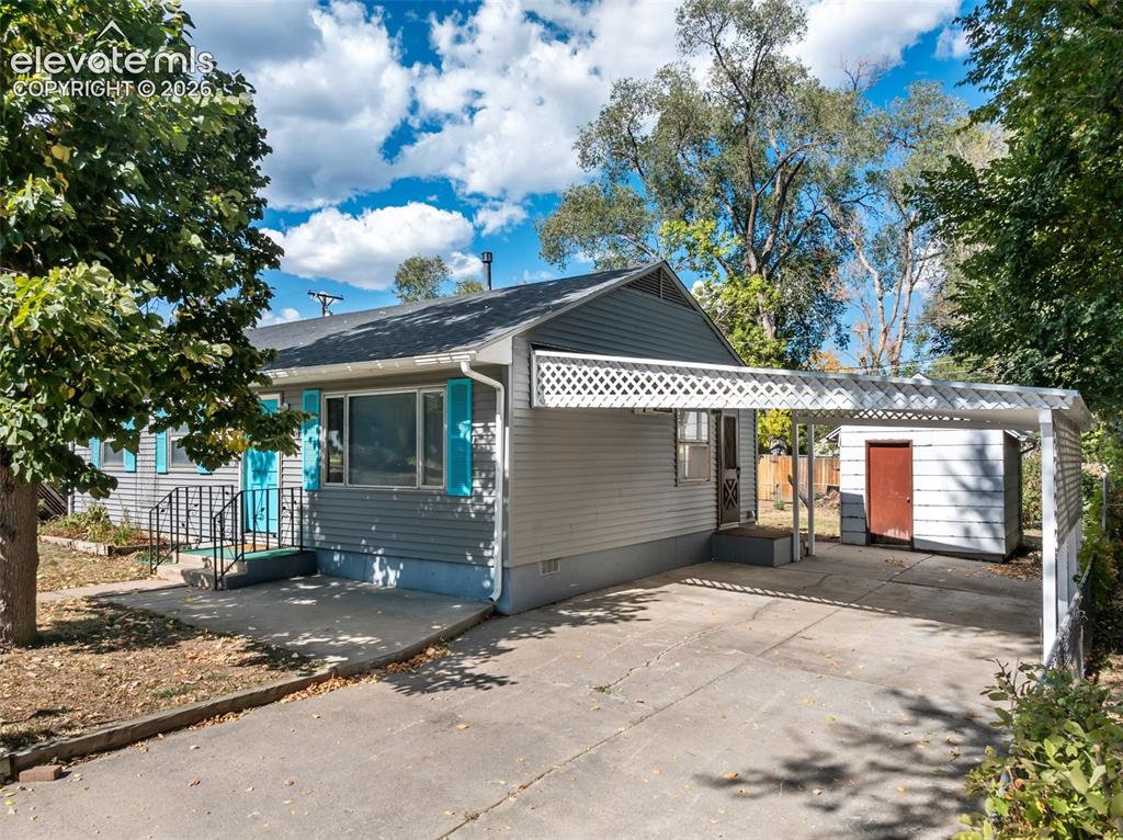 Image 5 of 45: Exterior featuring light gray siding, teal window shutters, and a covered c