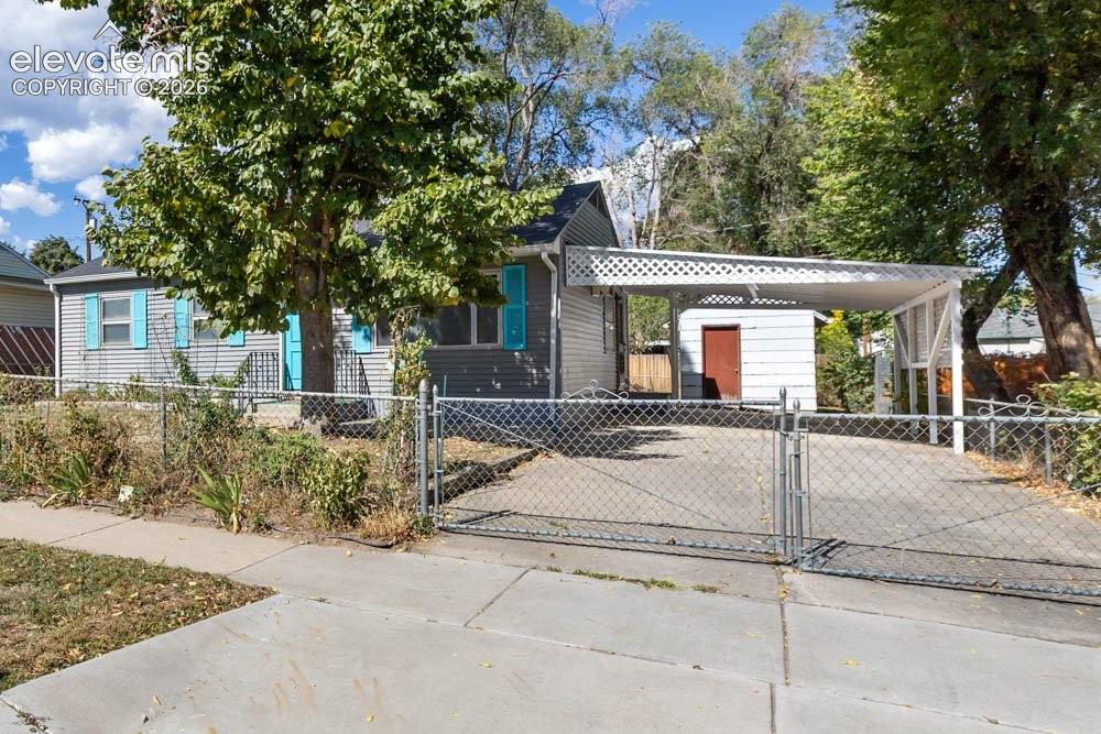 Image 6 of 45: Gray siding exterior with contrasting blue shutters, white carport structur