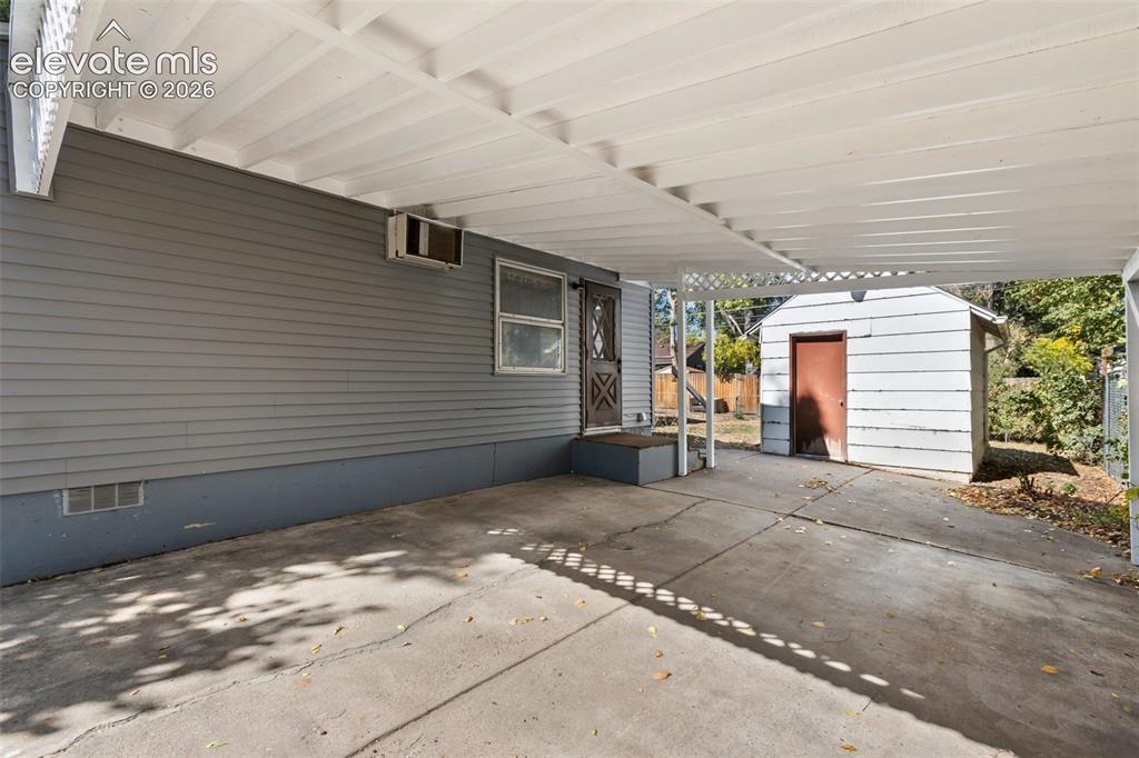 Image 7 of 45: Covered concrete patio with white lattice detailing