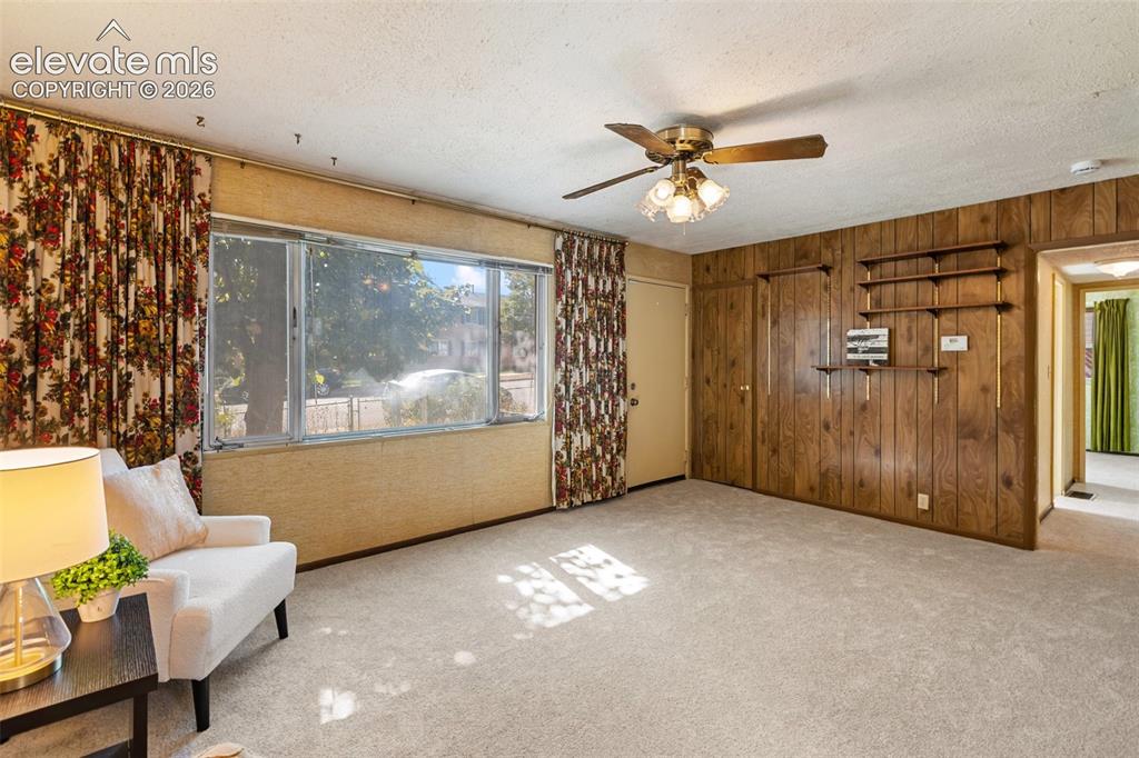 Image 8 of 45: Carpeted flooring, wood panel accent wall, built-in shelving, large window,