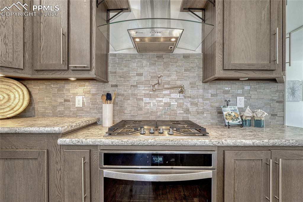 Image 11 of 48: Built-in oven under the gas cooktop along with a pot filler for added conve