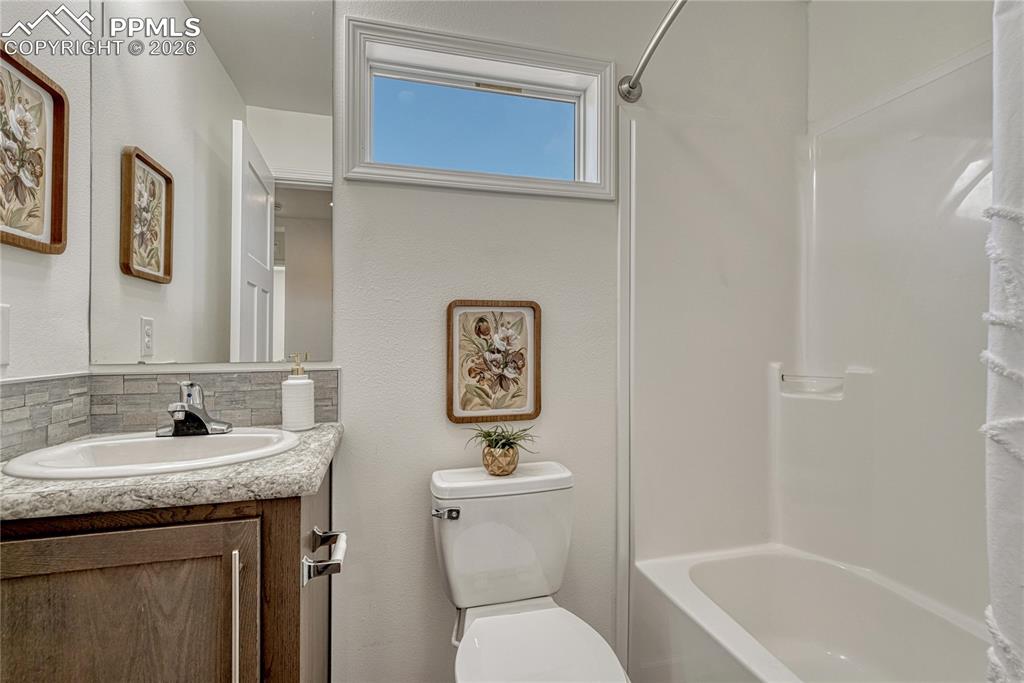 Image 19 of 48: Main level full bathroom off the hallway with matching countertop and backs