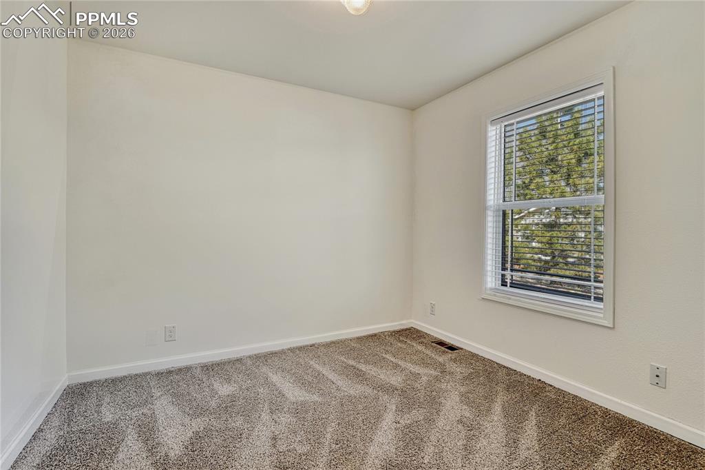 Image 21 of 48: Second main-level bedroom with carpet, vinyl windows and coverings
