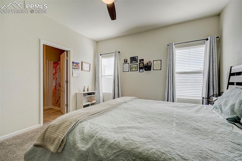 Image 18 of 45: Carpeted bedroom with ceiling fan and ensuite bathroom