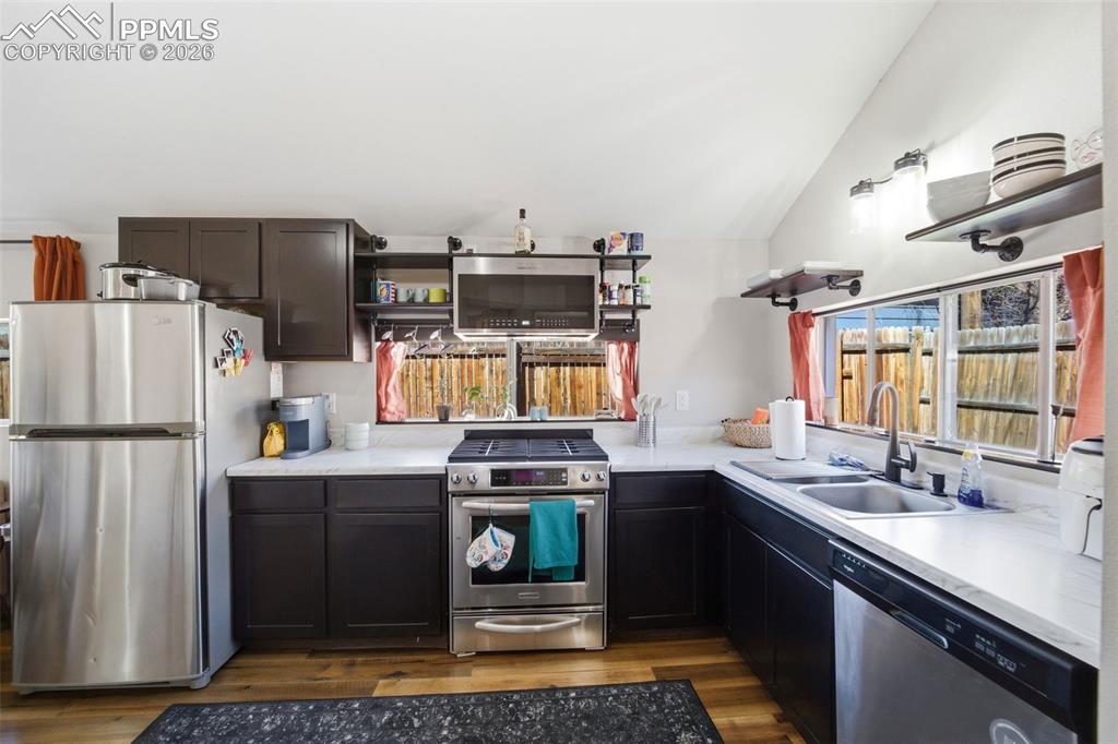 Image 22 of 35: Kitchen with stainless steel appliances, open shelves, and lofted ceiling