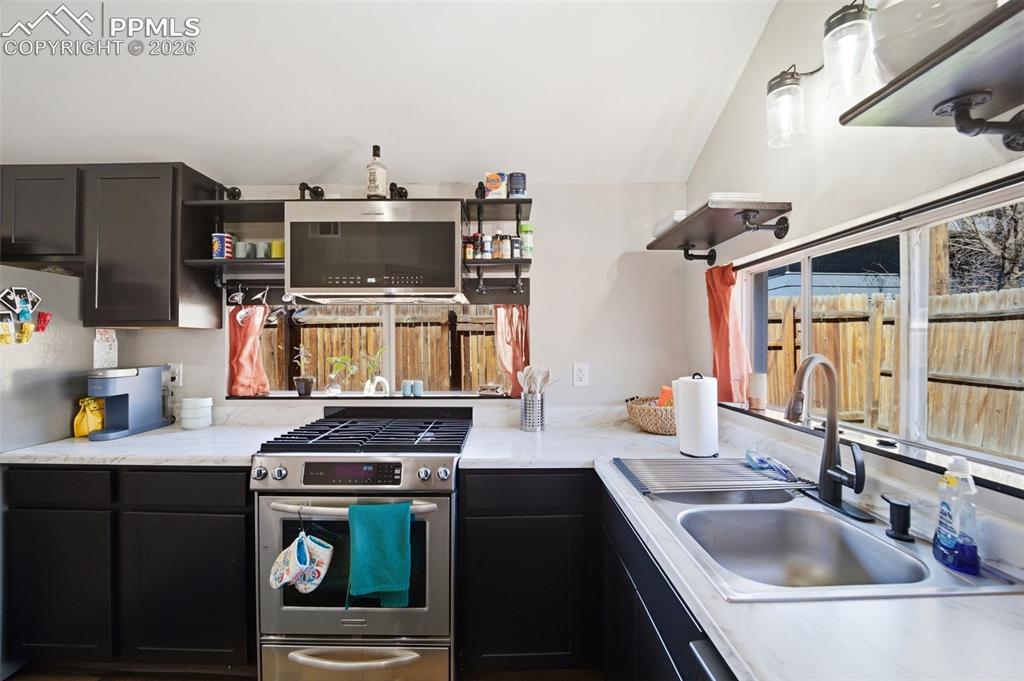 Image 23 of 35: Kitchen with stainless steel appliances, open shelves, dark cabinets, and p