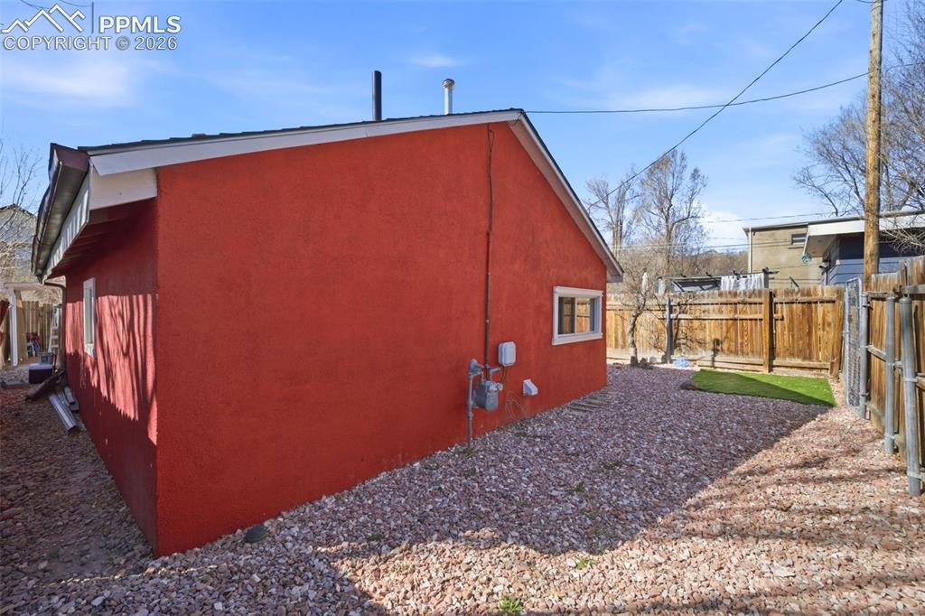 Image 31 of 35: View of back of cottage with a fenced backyard and stucco siding