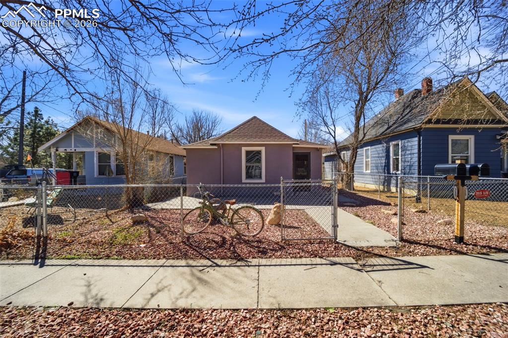 Image 33 of 35: View of back of cottage with a fenced backyard and stucco siding