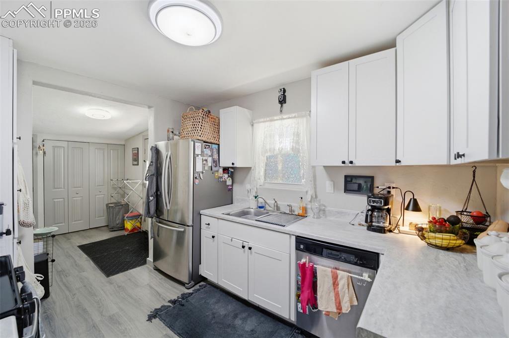 Image 6 of 35: Kitchen featuring light countertops, white cabinets, stainless steel applia