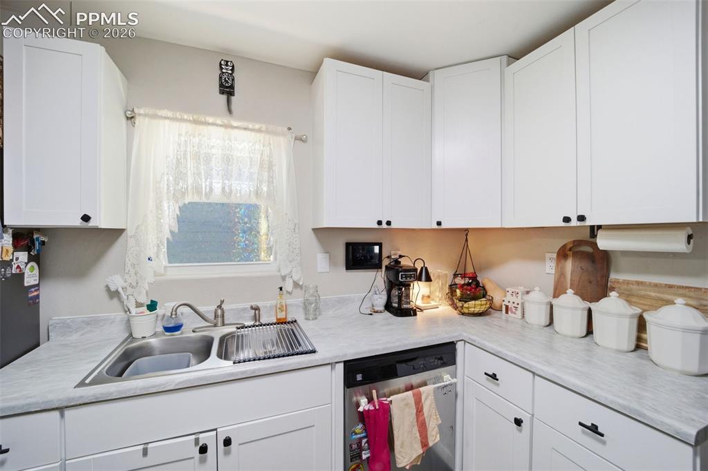 Image 7 of 35: Kitchen featuring light countertops, stainless steel dishwasher, and white