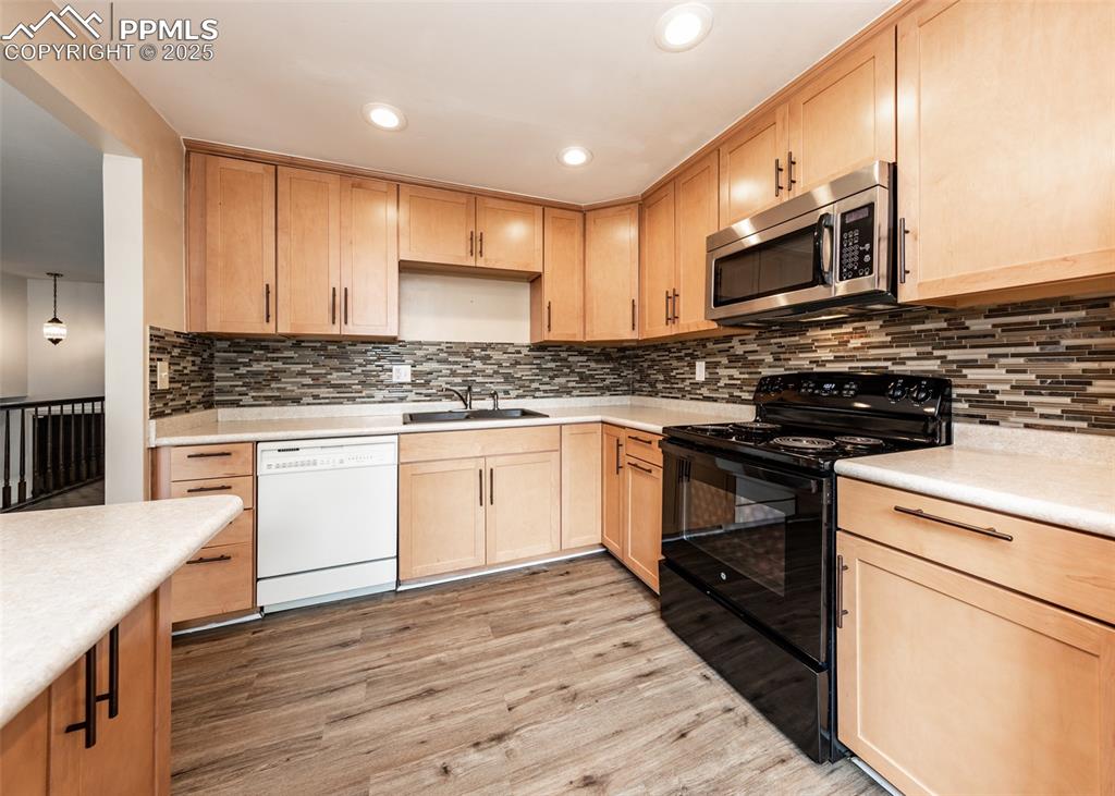 Image 7 of 22: Kitchen with light brown cabinetry, black / electric stove, stainless steel