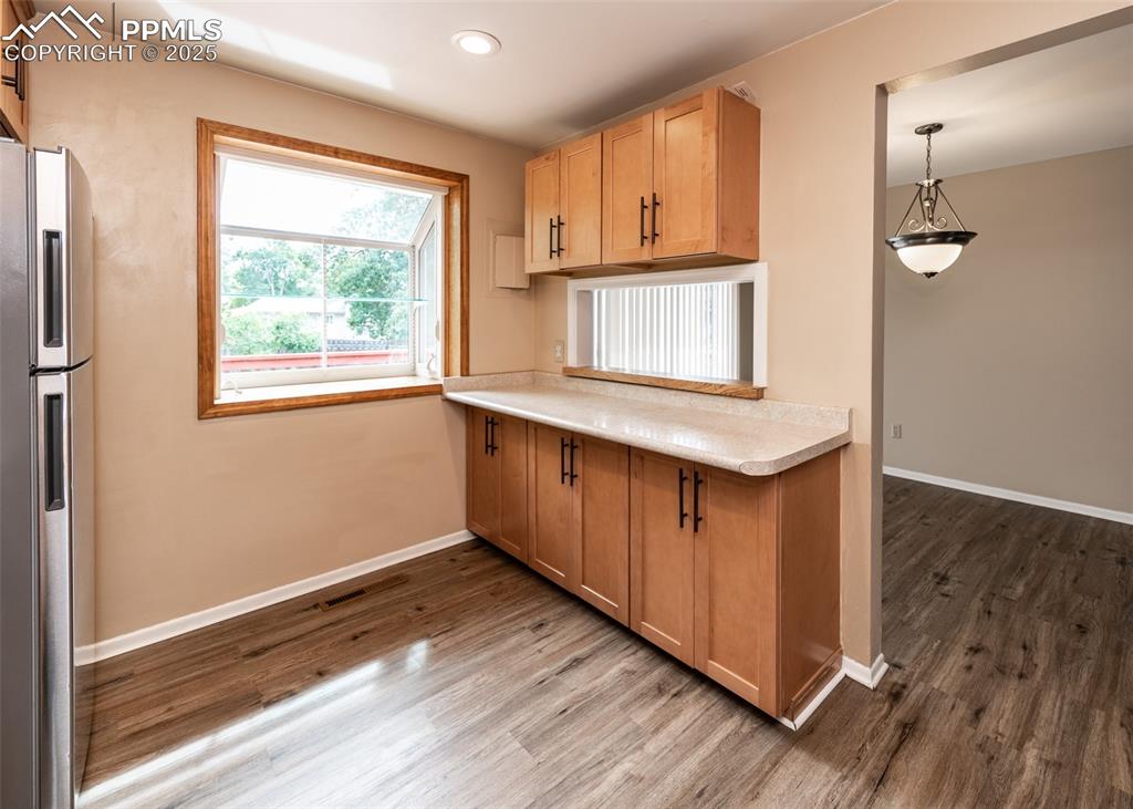 Image 8 of 22: Kitchen featuring freestanding refrigerator, light countertops, dark wood-s