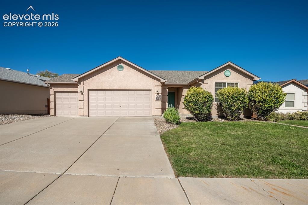 Caption: Single-story exterior featuring a stucco facade, gabled roofline, concrete driveway, and a three-car
