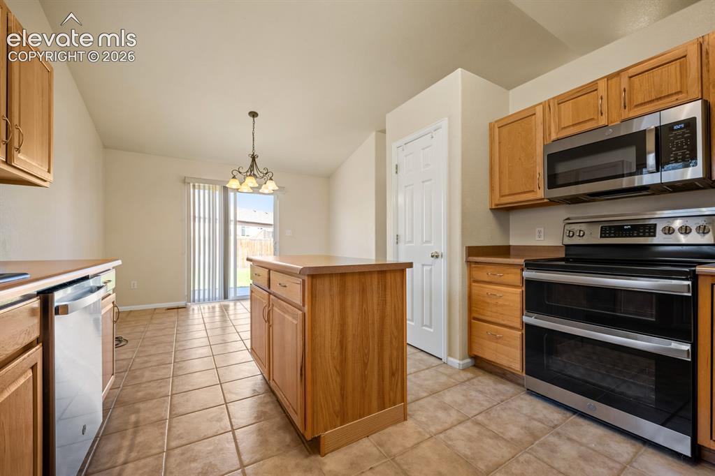 Image 11 of 33: Kitchen featuring wood cabinetry, stainless steel appliances, a center isla