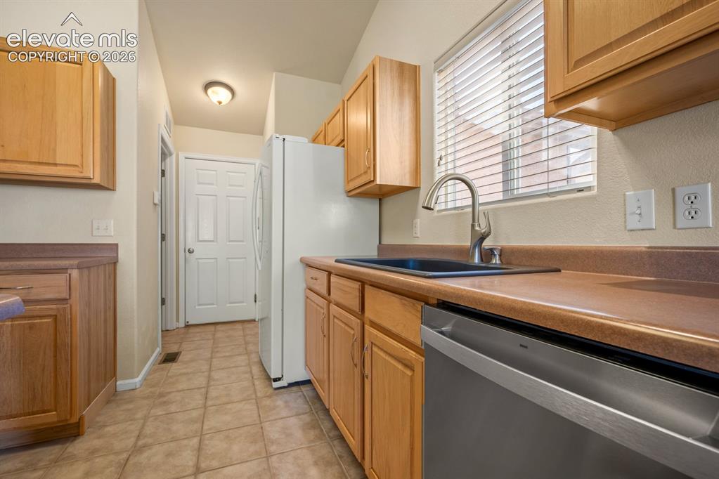 Image 12 of 33: Kitchen featuring light wood cabinetry, matte countertops, integrated stain