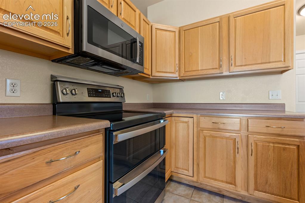 Image 13 of 33: Kitchen featuring light wood cabinetry, stainless steel double oven, over-t