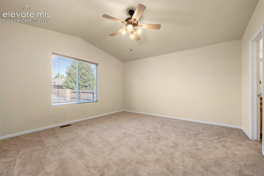 Image 15 of 33: Vaulted ceiling featuring a central multi-blade ceiling fan with integrated