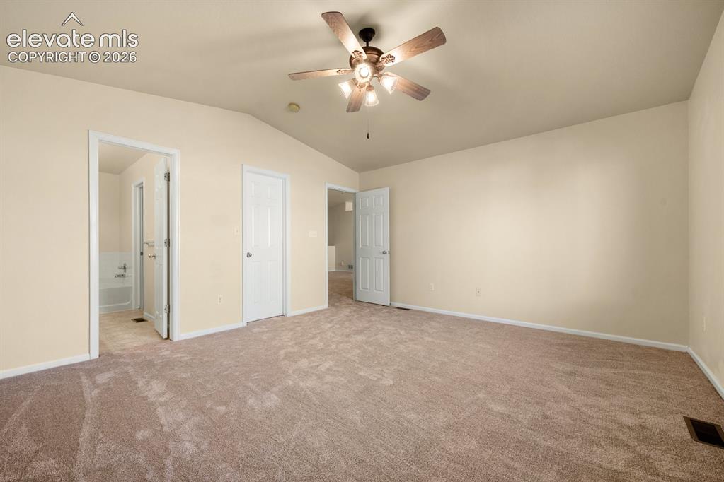 Image 16 of 33: Vaulted ceilings, neutral wall color, plush wall-to-wall carpeting, and a c