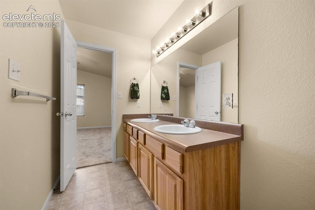 Image 18 of 33: Dual-sink vanity with a solid-surface countertop, full-width wall mirror, a