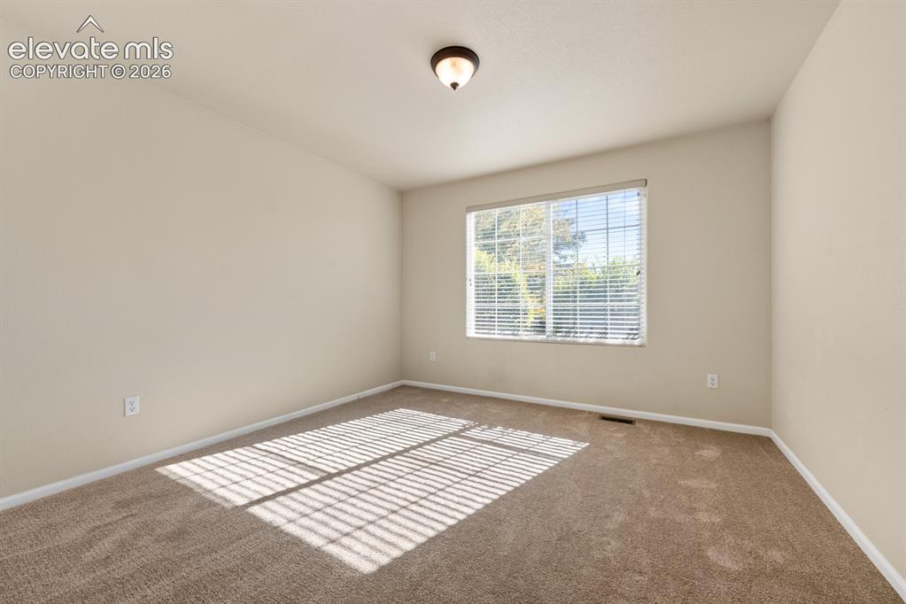 Image 20 of 33: Neutral-toned interior room featuring wall-to-wall carpeting, a multi-pane