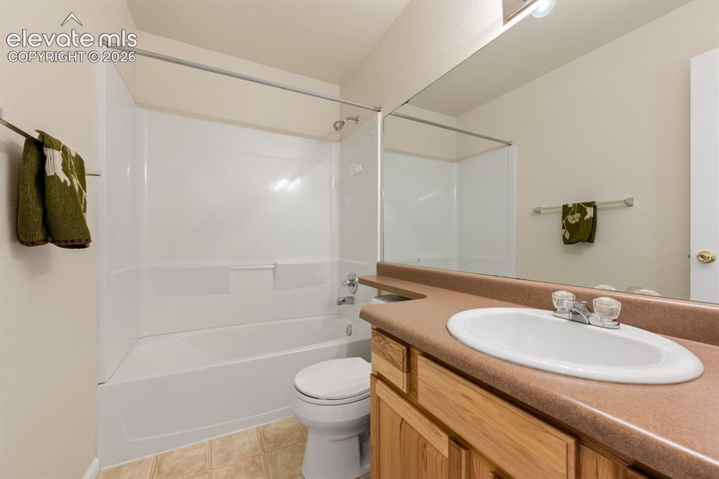 Image 22 of 33: Bathroom featuring a single-sink vanity with a solid-surface countertop, wo