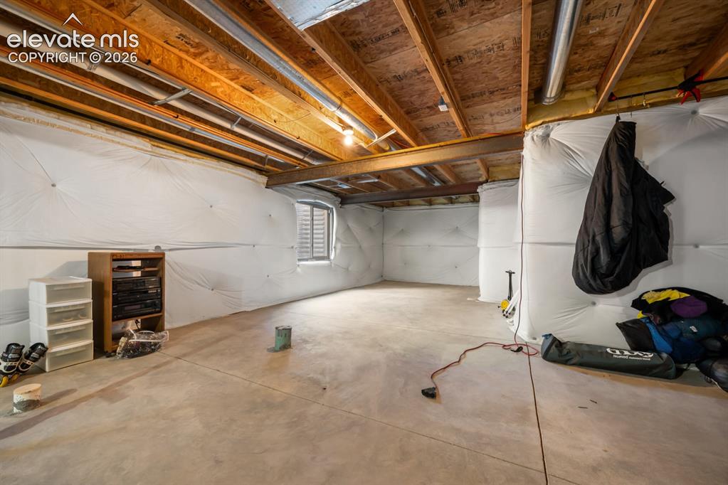 Image 28 of 33: Unfinished storage space featuring exposed wooden joists, poured concrete f