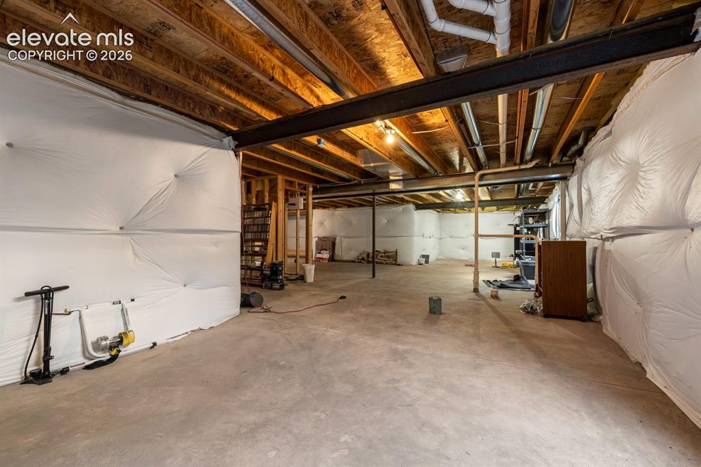 Image 29 of 33: Unfinished lower level featuring concrete flooring, exposed wood joist ceil