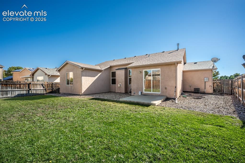 Image 31 of 33: Stucco exterior featuring a sliding glass door, concrete patio, gravel peri