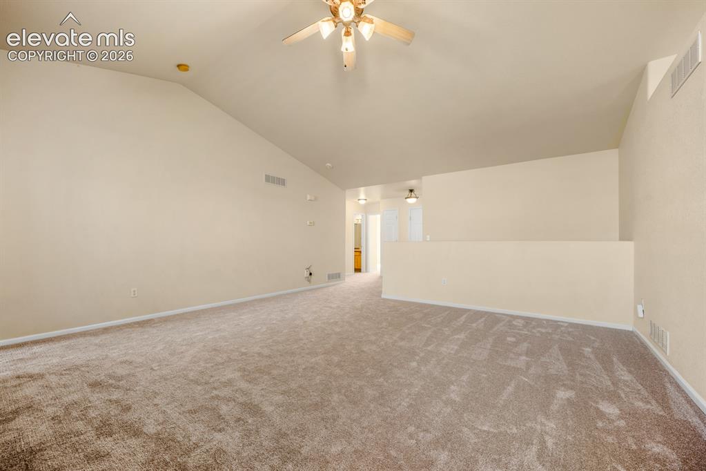 Image 7 of 33: Interior space featuring vaulted ceilings, neutral wall tones, wall-to-wall