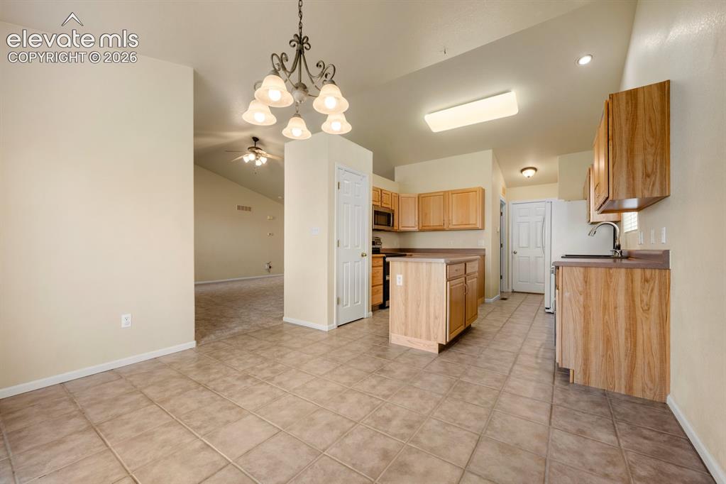 Image 9 of 33: Kitchen featuring wood cabinetry, central island, tile flooring, vaulted ce