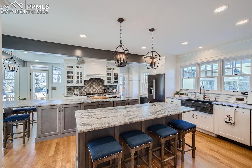 Image 11 of 49: Kitchen with light hardwood flooring, a kitchen island, white and gray cabi