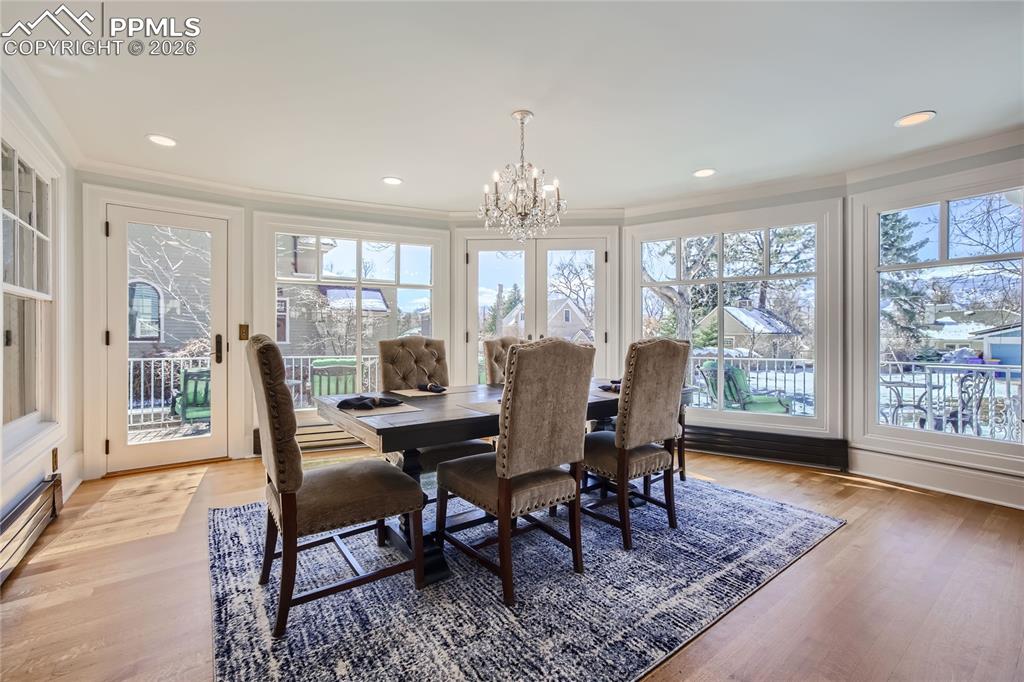 Image 12 of 49: Dining area featuring light hardwood floors, crown molding, and a chandelie