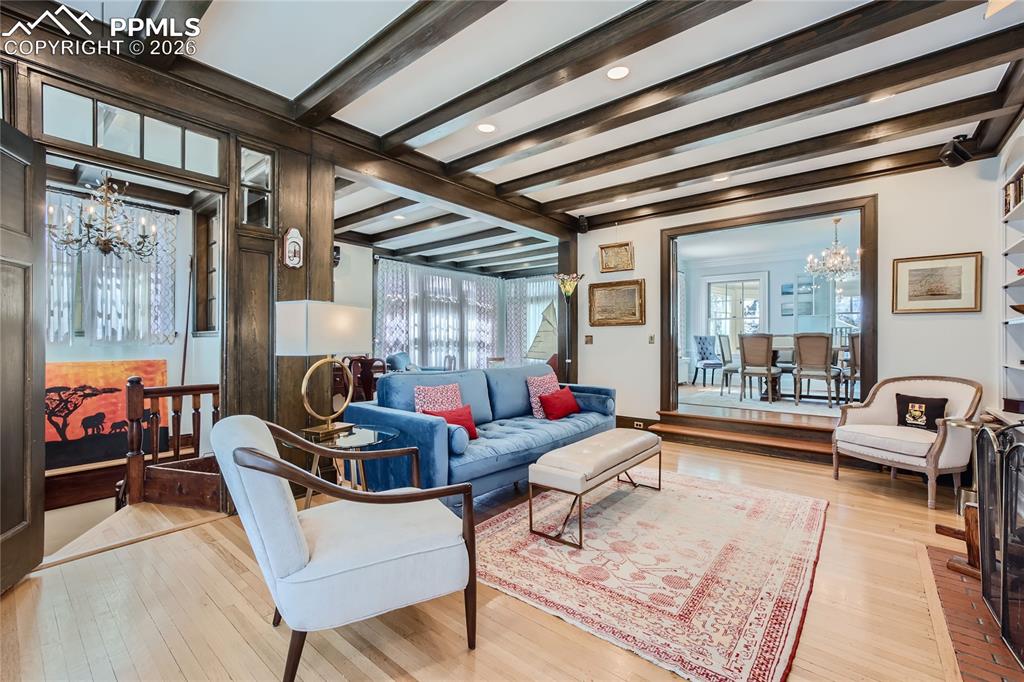 Image 17 of 49: Living room featuring an inviting chandelier, beamed ceiling, and light har