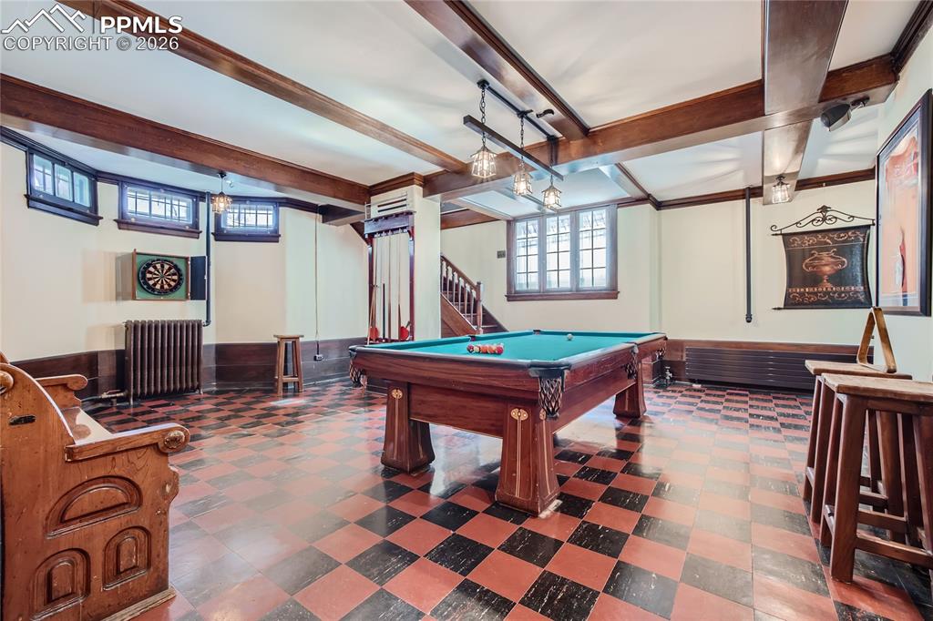 Image 23 of 49: Rec room with billiards, radiator, beamed ceiling, and dark tile floors
