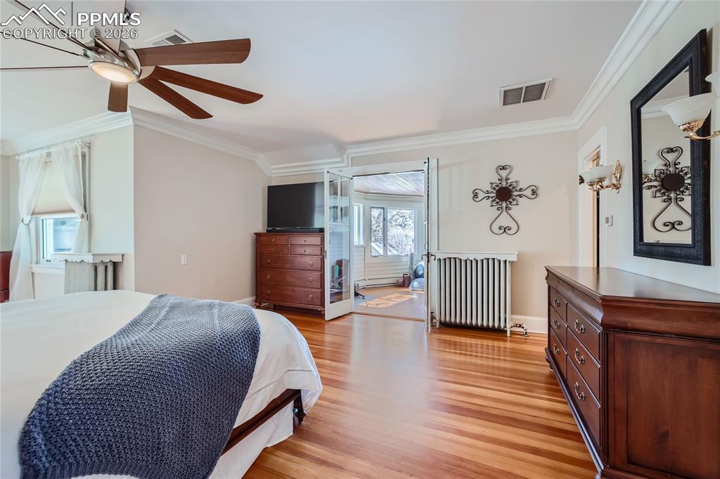 Image 30 of 49: Bedroom with ornamental molding, radiator, light wood flooring, and ceiling
