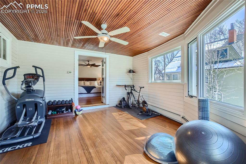 Image 33 of 49: Workout room with wood ceiling, wood walls, ceiling fan, and light hardwood