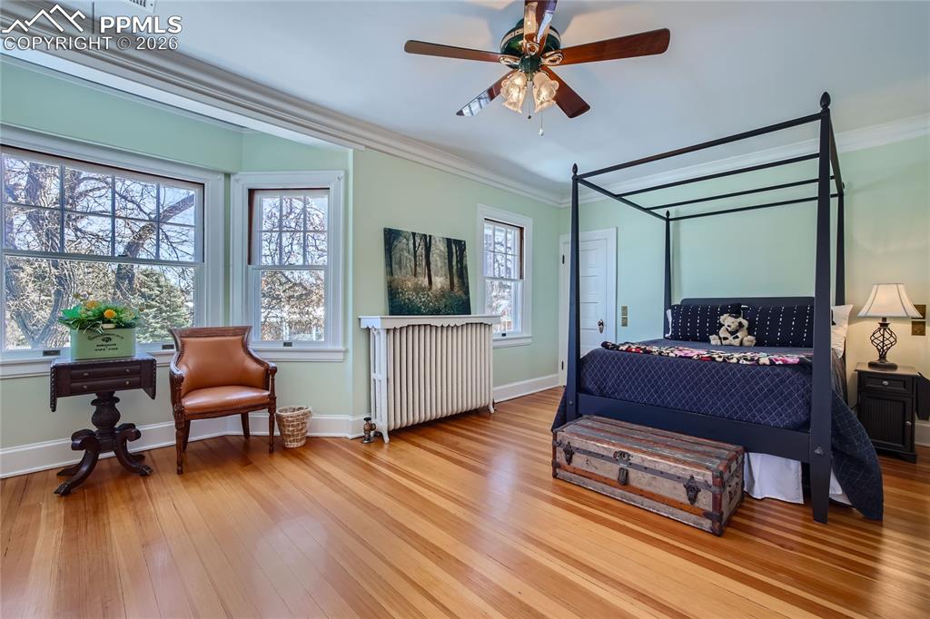 Image 34 of 49: Bedroom with radiator, light hardwood floors, ornamental molding, and ceili