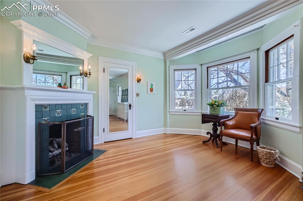 Image 35 of 49: Living area with a fireplace, crown molding, and light hardwood floors