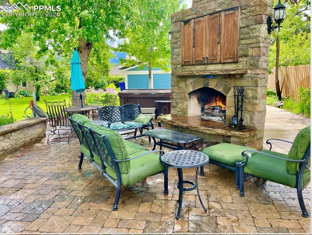 Image 6 of 49: View of patio / terrace with an outdoor stone fireplace, with Gas