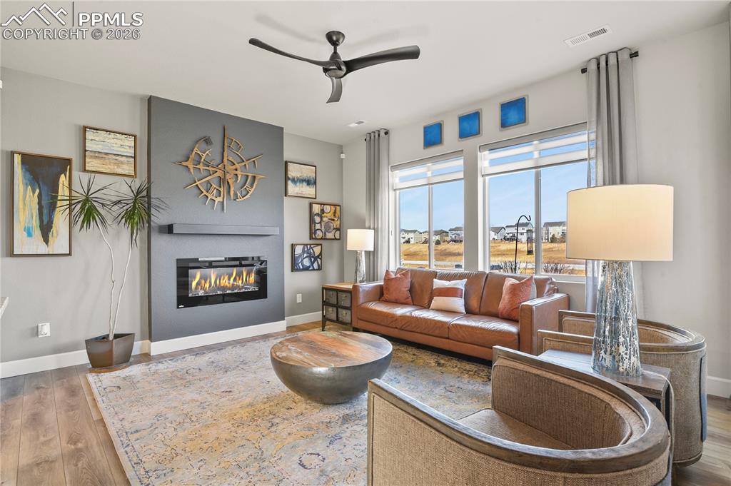 Image 8 of 27: The living room is anchored by a sleek electric fireplace