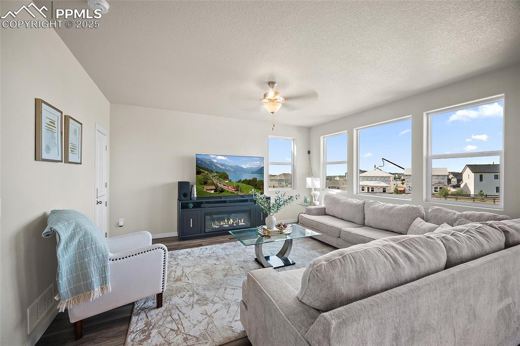 Image 15 of 41: Living room featuring wood finished floors, a ceiling fan, a glass covered